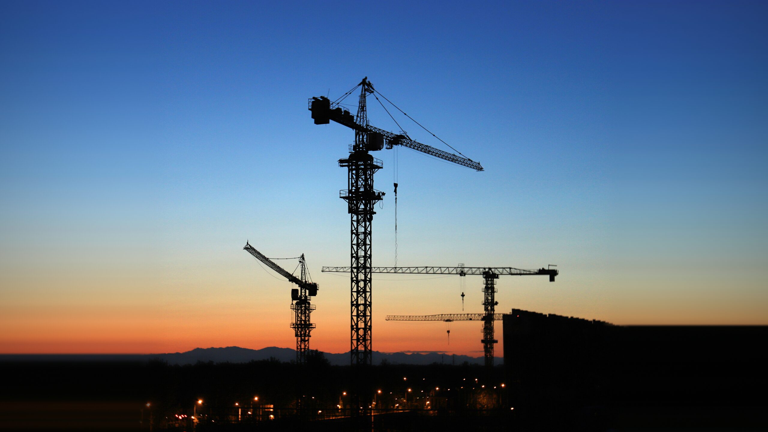 Torenkranen in silhouet bij zonsondergang — Heistech kraantechniek