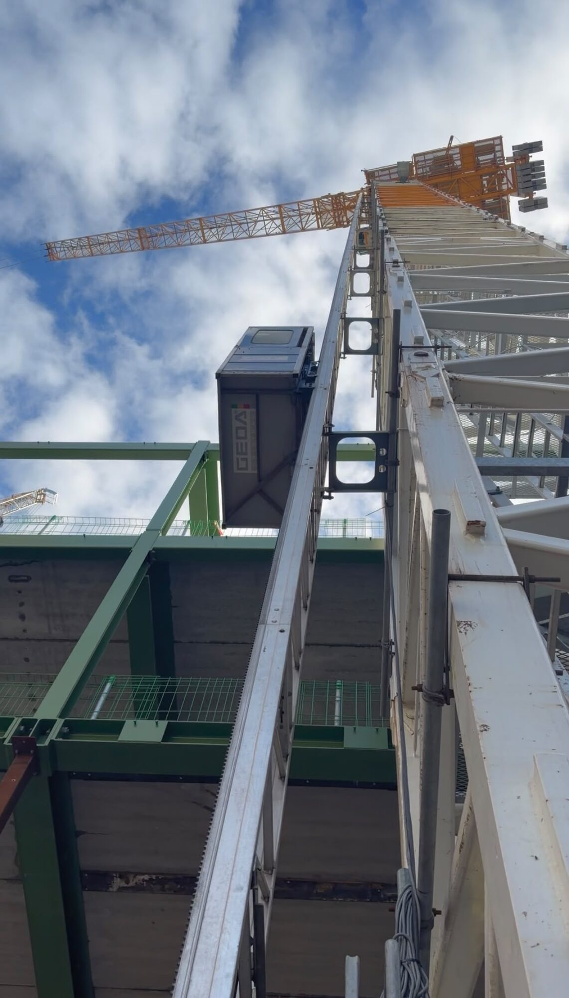 Geda bouwlift langs de mast met torenkraan op de achtergrond